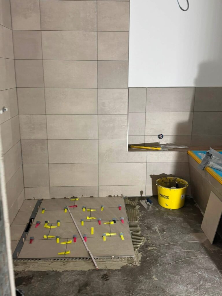 Duschbereich mit Wandfliesen und Bodenfliesen während der Verlegung
